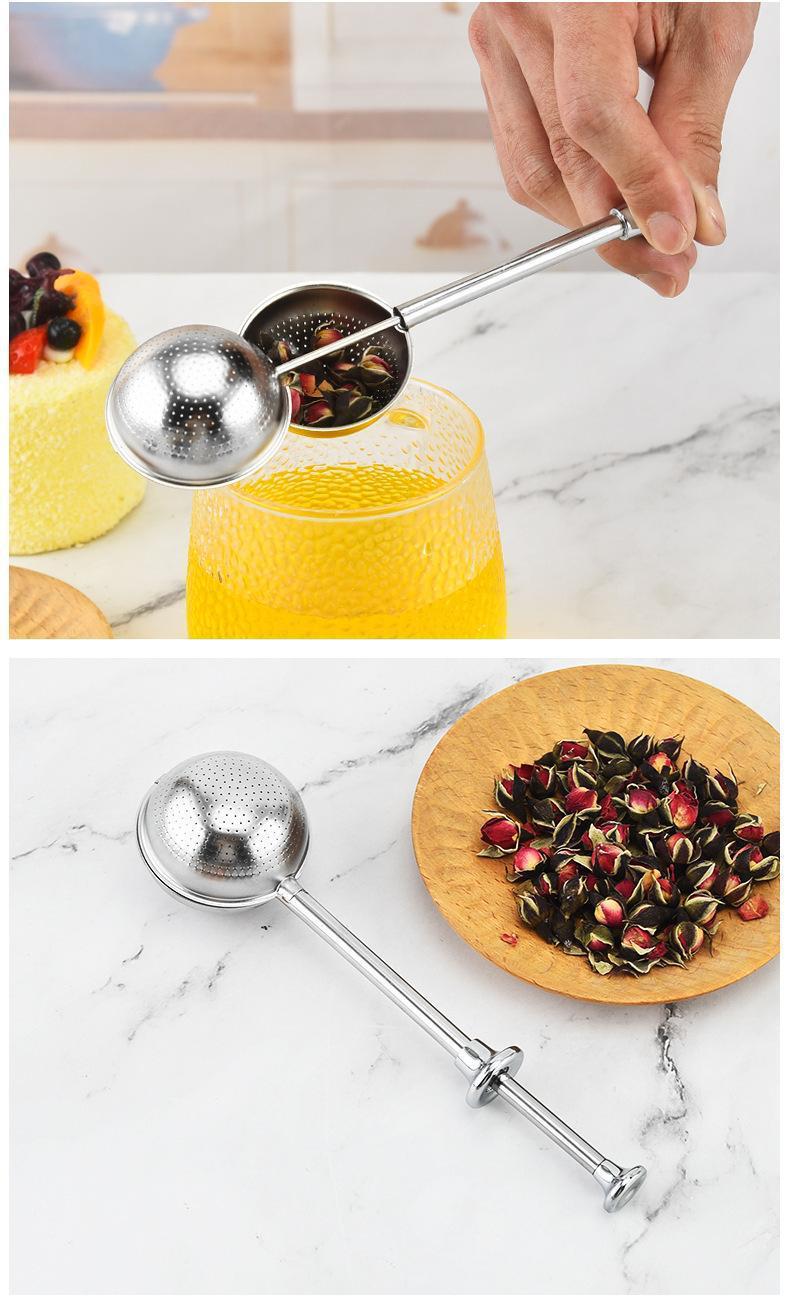Infusore a spinta in acciaio inox aperto sopra una tazza di tè, con boccioli di rosa sul piatto
